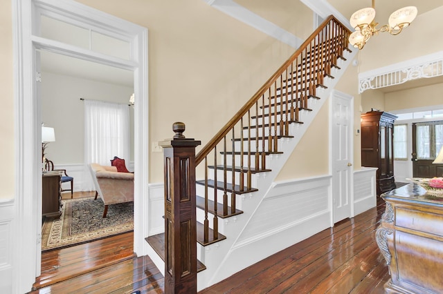 stairs featuring a decorative wall, a notable chandelier, wainscoting, and hardwood / wood-style flooring