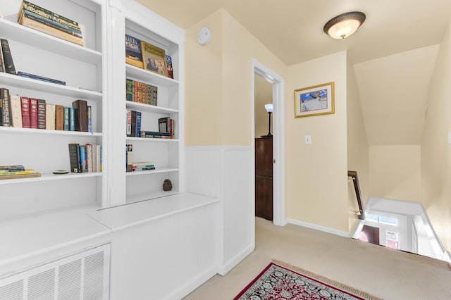 hallway featuring carpet and a wainscoted wall