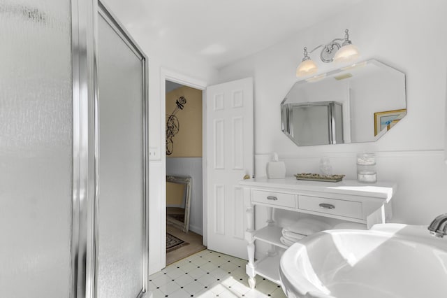 bathroom featuring tile patterned floors, a shower with door, and a sink