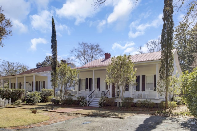 view of front of home featuring a porch, a chimney, and metal roof