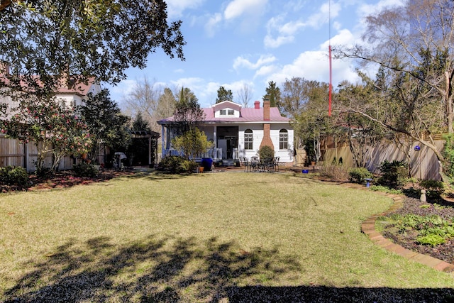 exterior space featuring a lawn, metal roof, and fence