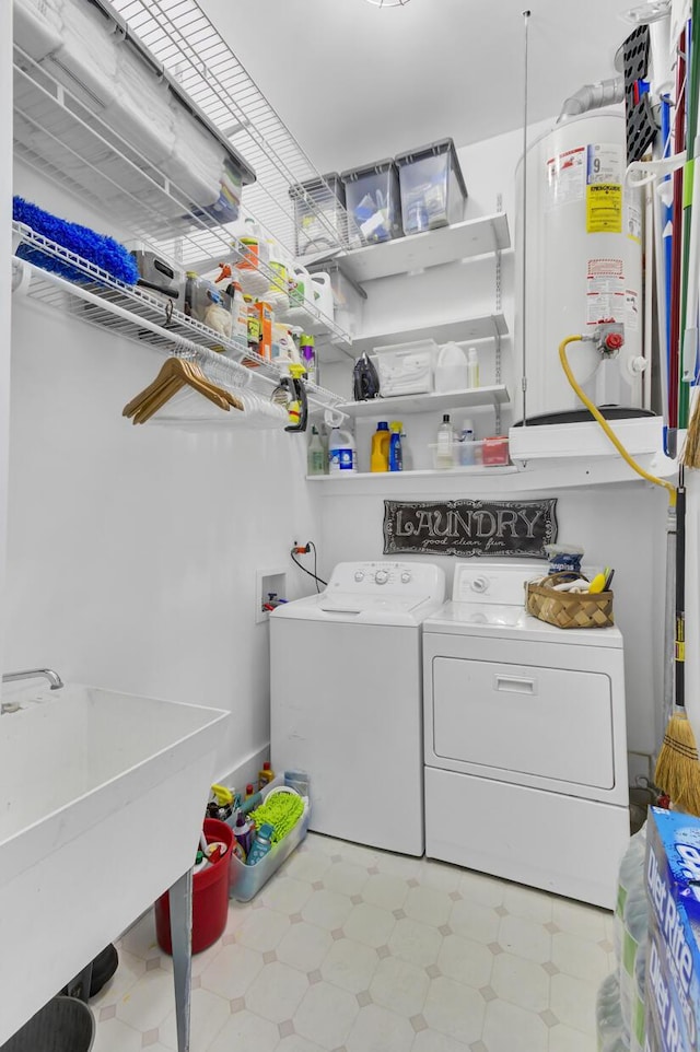 clothes washing area featuring washing machine and clothes dryer, gas water heater, laundry area, tile patterned floors, and a sink