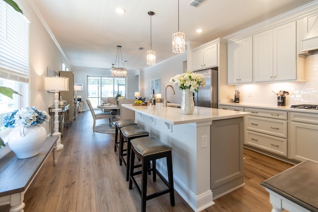 754 Blue Iris Way, Summerville, SC 29486 - kitchen with appliances with stainless steel finishes, ornamental molding, decorative backsplash, light countertops, and a center island with sink