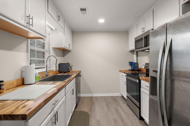 kitchen featuring white cabinetry, appliances with stainless steel finishes, butcher block counters, and sink