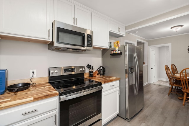 kitchen with butcher block countertops, white cabinetry, stainless steel appliances, crown molding, and light hardwood / wood-style flooring