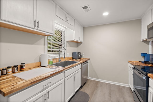 kitchen with sink, appliances with stainless steel finishes, light hardwood / wood-style floors, white cabinets, and wood counters