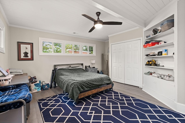 bedroom featuring crown molding, ceiling fan, wood-type flooring, a closet, and beamed ceiling