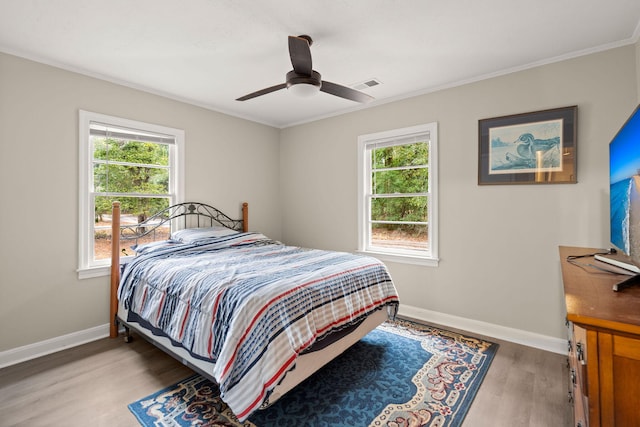 bedroom featuring crown molding, ceiling fan, hardwood / wood-style floors, and multiple windows