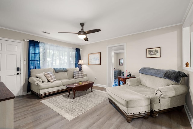 living room with wood-type flooring, ornamental molding, and ceiling fan