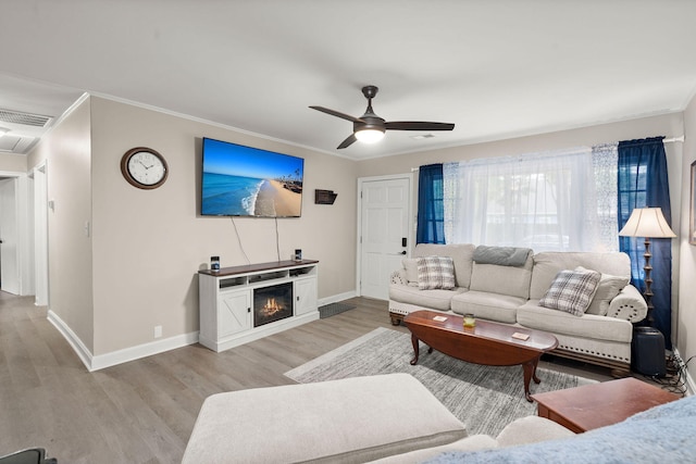 living room featuring ceiling fan, ornamental molding, and light hardwood / wood-style flooring