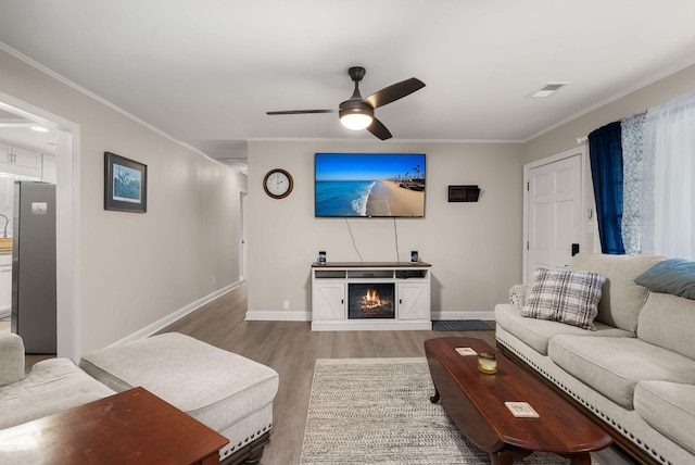 living room with hardwood / wood-style flooring, crown molding, and ceiling fan