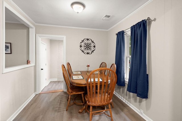 dining area with crown molding and wood-type flooring