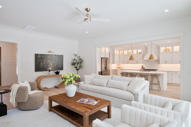 living room with crown molding, recessed lighting, visible vents, a ceiling fan, and light wood-type flooring