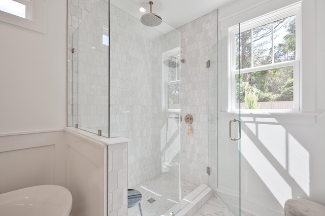 bathroom featuring a wainscoted wall, marble finish floor, and a stall shower