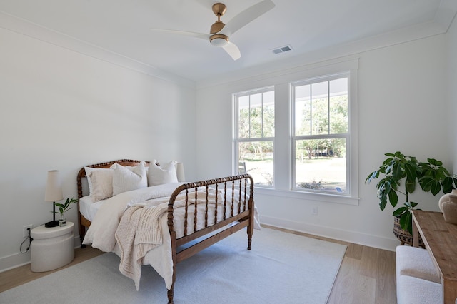 bedroom with visible vents, crown molding, baseboards, and wood finished floors