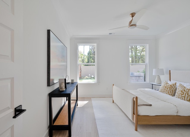 bedroom with multiple windows, wood finished floors, visible vents, and baseboards