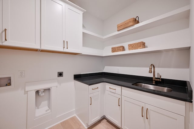 clothes washing area featuring cabinet space, light wood finished floors, a sink, hookup for a washing machine, and electric dryer hookup