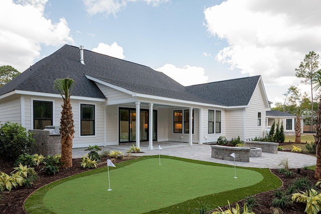 rear view of house featuring a fire pit, a shingled roof, and a patio area