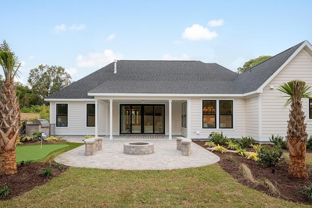 back of property featuring roof with shingles, a fire pit, and a patio