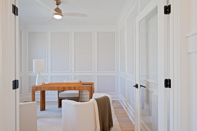 office space featuring a ceiling fan, a decorative wall, and wood finished floors