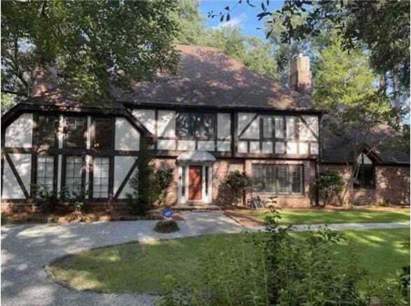 english style home featuring driveway, a front lawn, and a chimney