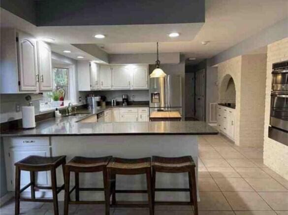 104 Legend Oaks Way, Summerville, SC 29485 - kitchen with a peninsula, dark countertops, light tile patterned floors, and stainless steel fridge with ice dispenser