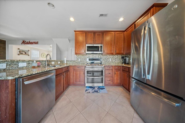 kitchen featuring light stone countertops, visible vents, a sink, decorative backsplash, and stainless steel appliances