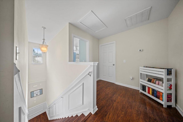 hallway featuring dark wood-type flooring, attic access, baseboards, and visible vents