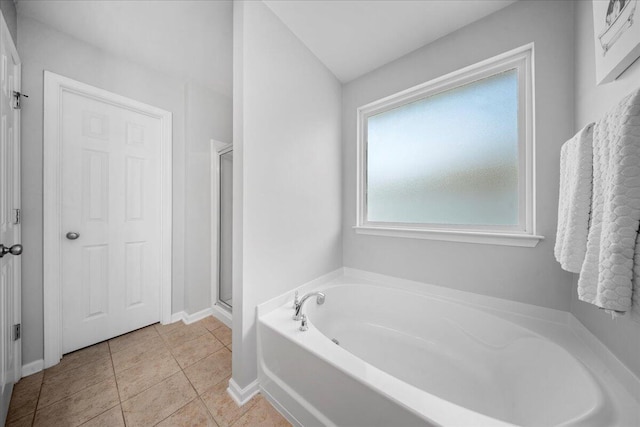 bathroom featuring a shower stall, a garden tub, baseboards, and tile patterned floors