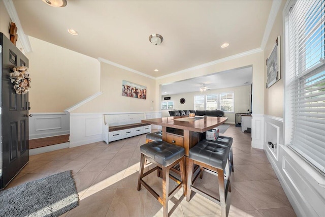 dining room featuring light tile patterned floors, a decorative wall, a wainscoted wall, and ornamental molding