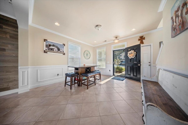 tiled dining area featuring recessed lighting, a wainscoted wall, crown molding, and a decorative wall