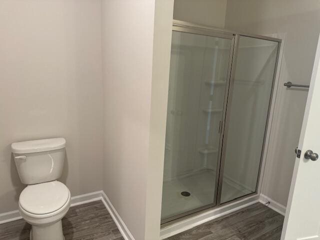 bathroom featuring wood-type flooring, toilet, and a shower with shower door