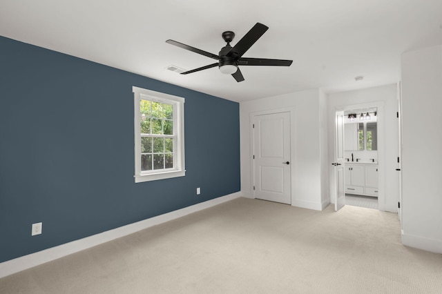 unfurnished bedroom with connected bathroom, light colored carpet, and ceiling fan