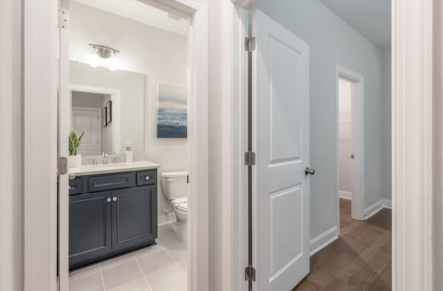 bathroom featuring toilet, vanity, baseboards, and wood finished floors