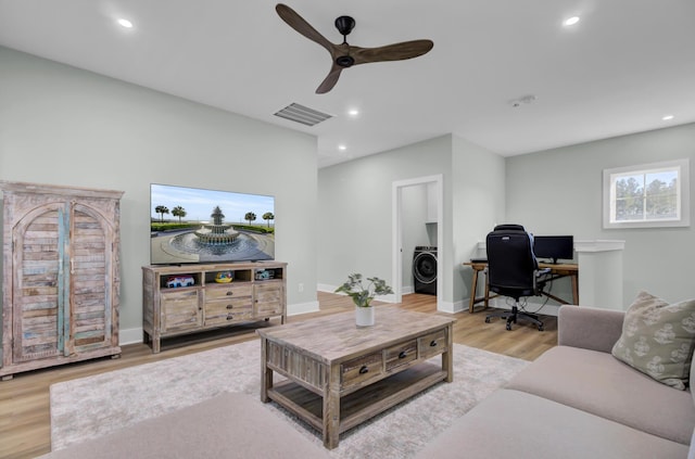 living room with washer / clothes dryer, ceiling fan, and light hardwood / wood-style flooring