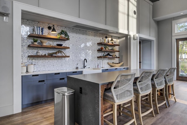 bar with blue cabinets, sink, hardwood / wood-style floors, and backsplash