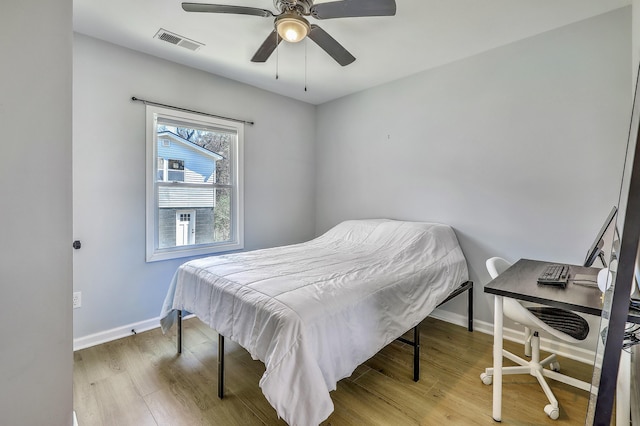 bedroom featuring visible vents, a ceiling fan, baseboards, and wood finished floors