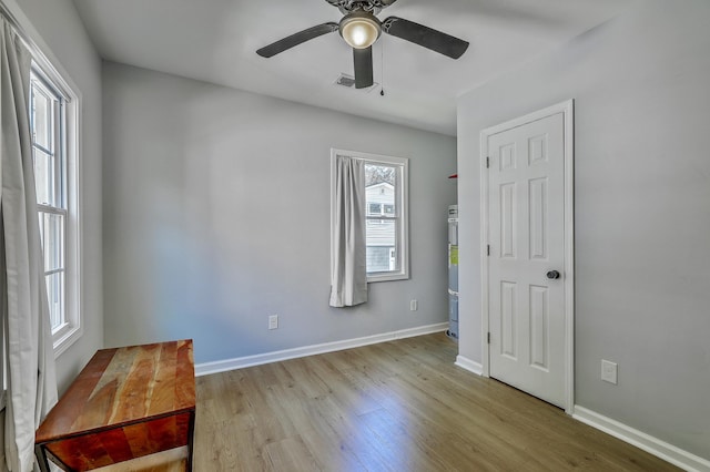 unfurnished bedroom with ceiling fan, visible vents, baseboards, and wood finished floors