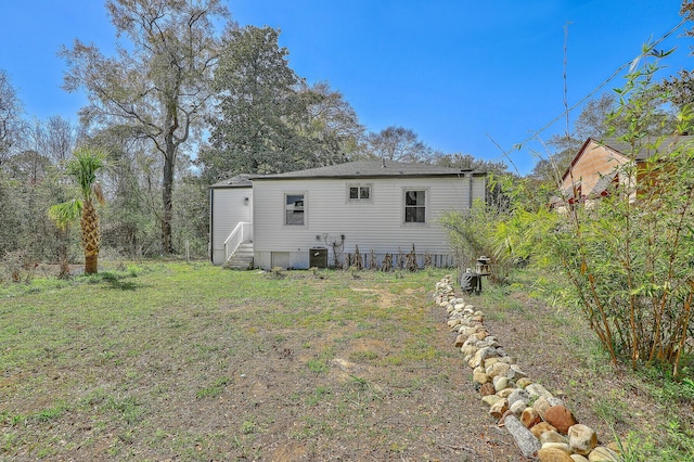 back of house with entry steps, a yard, and central AC