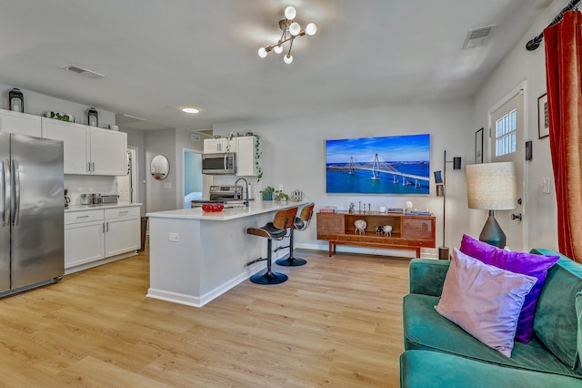 kitchen featuring light wood finished floors, visible vents, a kitchen breakfast bar, and stainless steel appliances