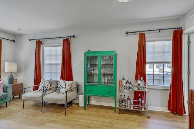 sitting room with visible vents, a bar, baseboards, and wood finished floors