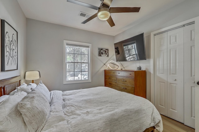 bedroom with visible vents, multiple windows, light wood-style floors, and a closet