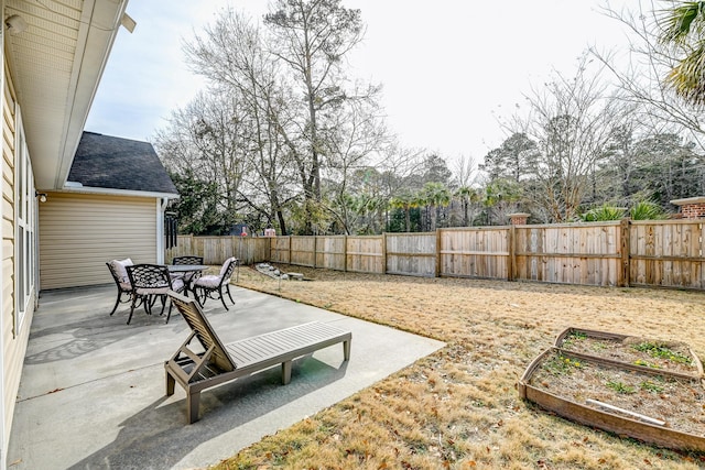 view of yard featuring a garden, a fenced backyard, a patio, and outdoor dining space