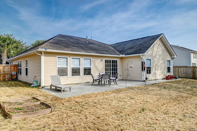 rear view of property featuring a vegetable garden, fence, a lawn, and a patio