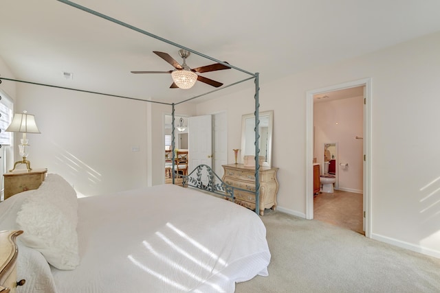 bedroom featuring visible vents, light carpet, ceiling fan, ensuite bath, and baseboards