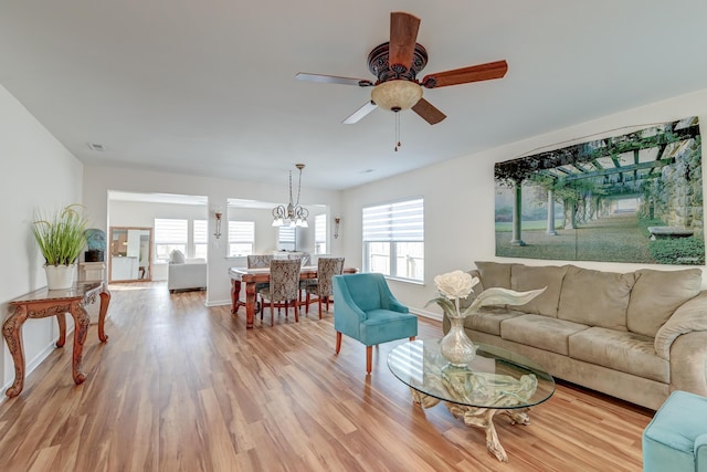 living area with ceiling fan with notable chandelier, a healthy amount of sunlight, visible vents, and wood finished floors