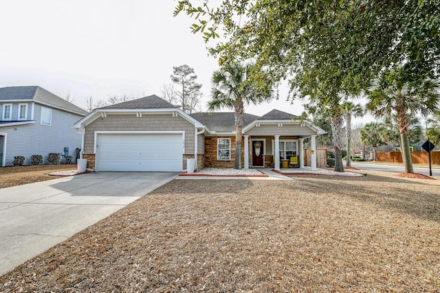 view of front of property with driveway, stone siding, an attached garage, and a shingled roof