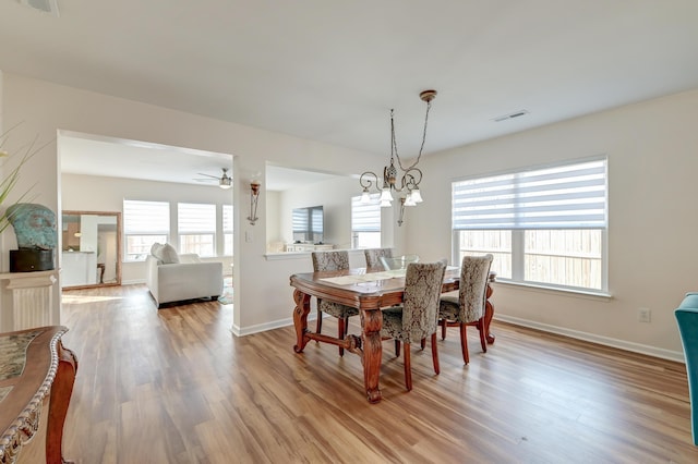 dining space featuring light wood-type flooring, visible vents, baseboards, and ceiling fan with notable chandelier