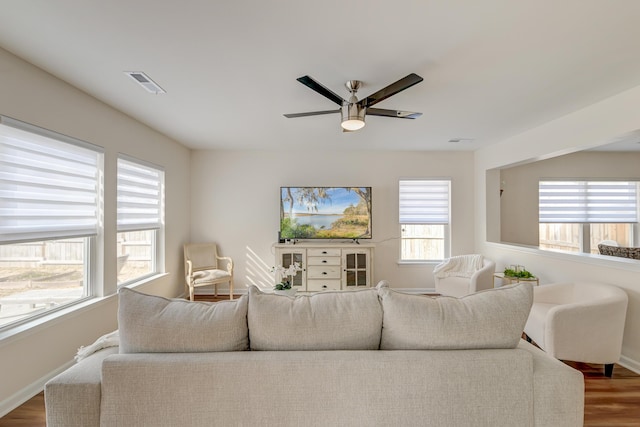 living room featuring ceiling fan, wood finished floors, visible vents, and baseboards