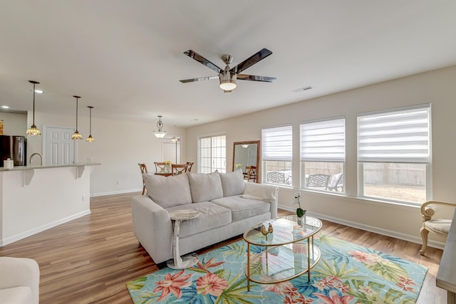 living room with light wood finished floors, baseboards, visible vents, a ceiling fan, and recessed lighting